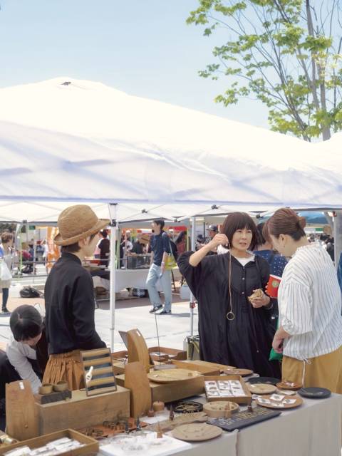 木の雑貨を前に来場者と話す店主たち